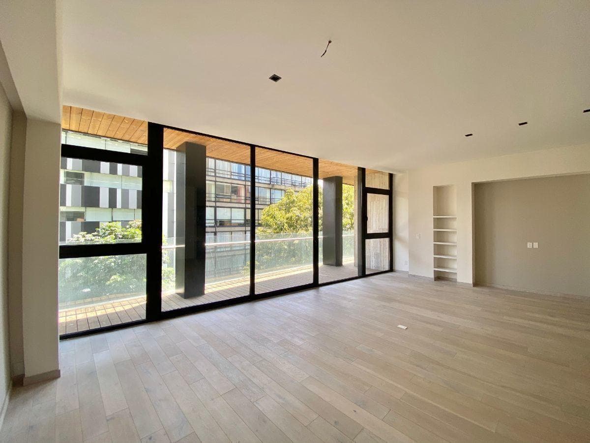 Sala vacía con piso de madera clara y ventanales negros