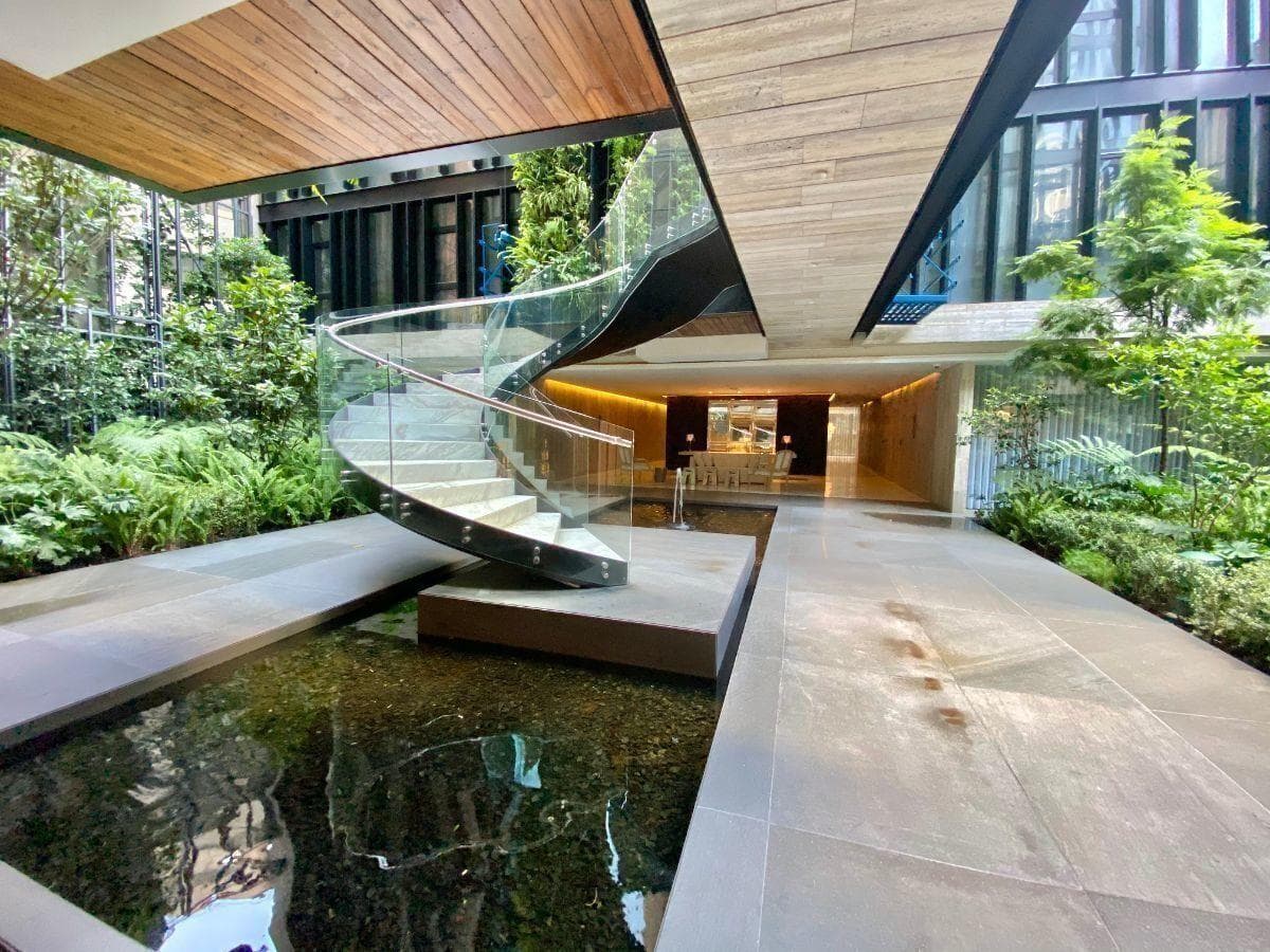 Patio con estanque y escalera helicoidal de cristal en una casa de Lomas de Chapultepec