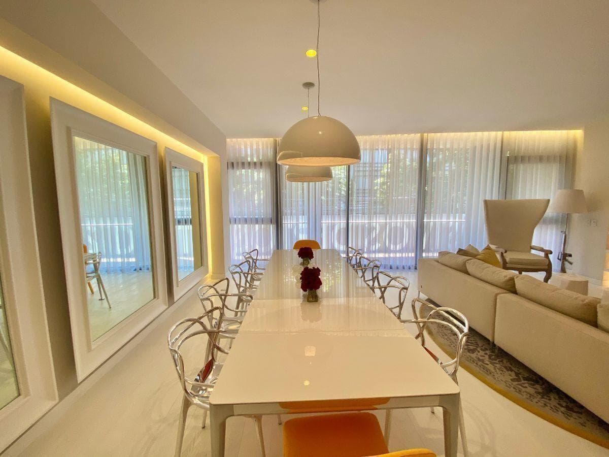 Comedor blanco con lámparas colgantes y sillas transparentes